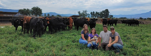 The Houseweart family seated in front of their cows in a pasture.